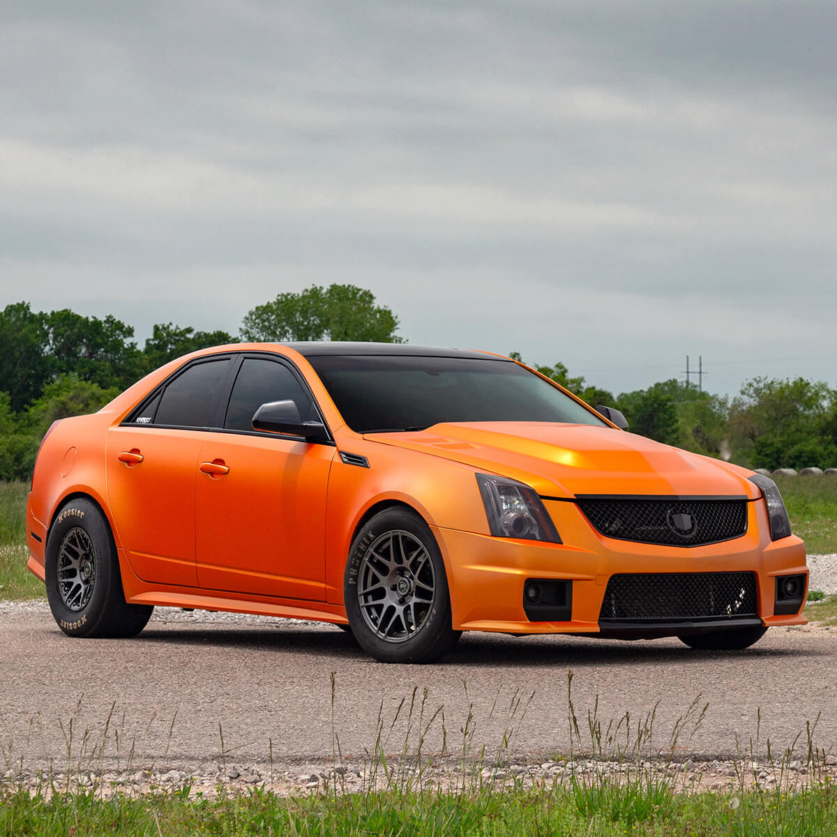 modified Cadillac CTS-V with drag tires black grille, tinted headlights and custom hood
